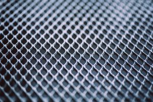 Surface of latticed metal fence. Stainless steel and aluminum light blur background. Macro texture