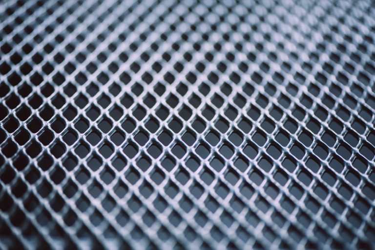 Surface of latticed metal fence. Stainless steel and aluminum light blur background. Macro texture