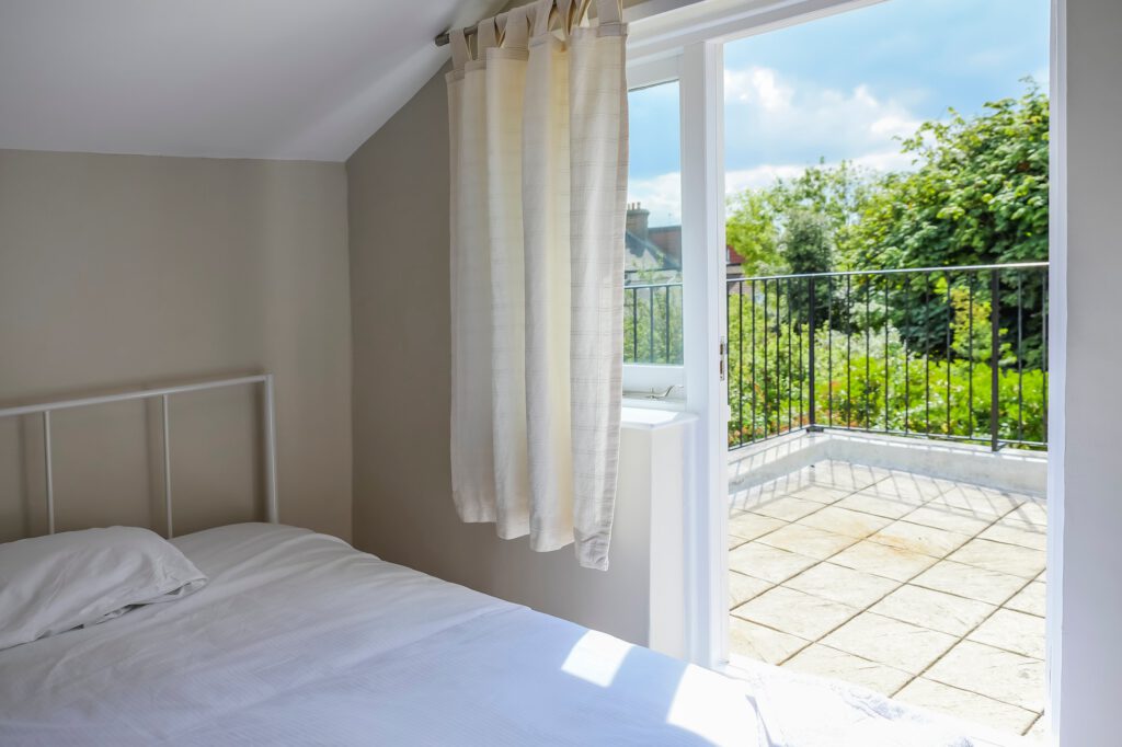 Attic bedroom with balcony and greenery view.