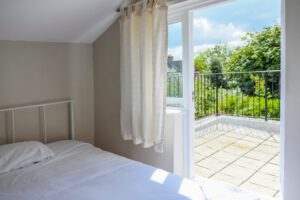 Attic bedroom with balcony and greenery view.